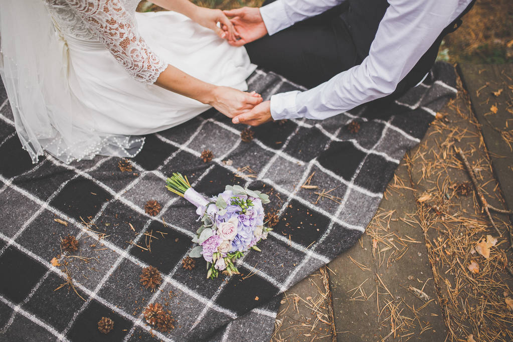 stock photo enamored bride and groom are sitting on a plaid plaid holding hands a wedding bouquet