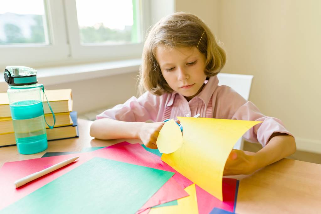 stock photo female child sits at home at the table near the window scissors colored paper makes